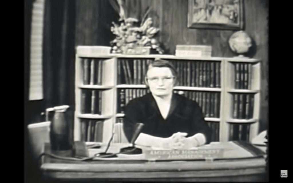 A woman sitting at a desk in front of books.