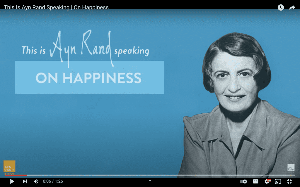 A woman is smiling and standing in front of the words " speaking on happiness ".