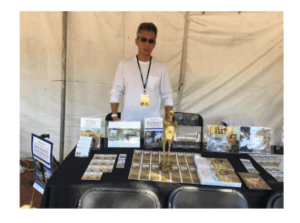 Vendor at booth displaying jewelry and awards