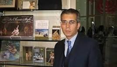 Man in suit standing by bookshelves
