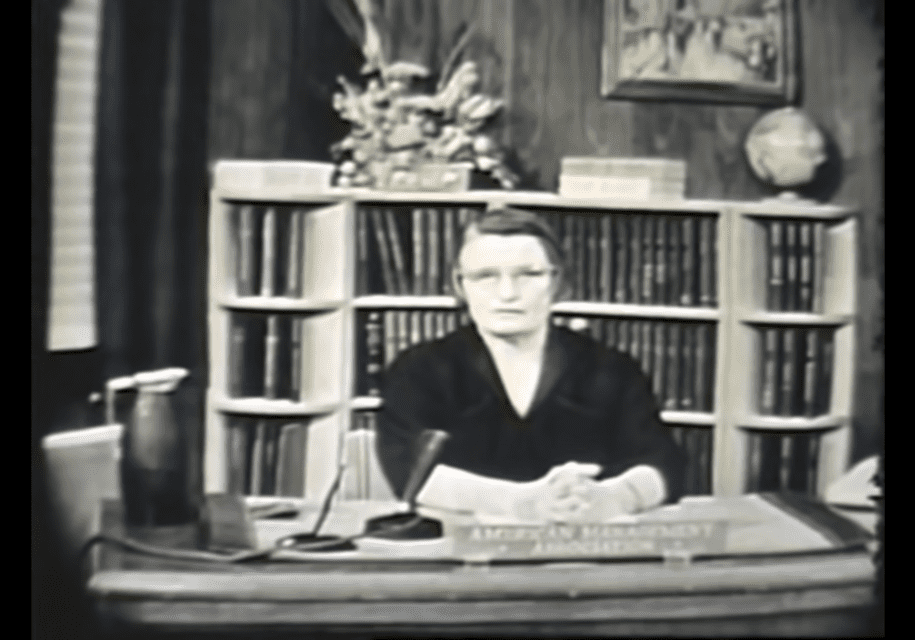 A woman sitting at a desk in front of books.