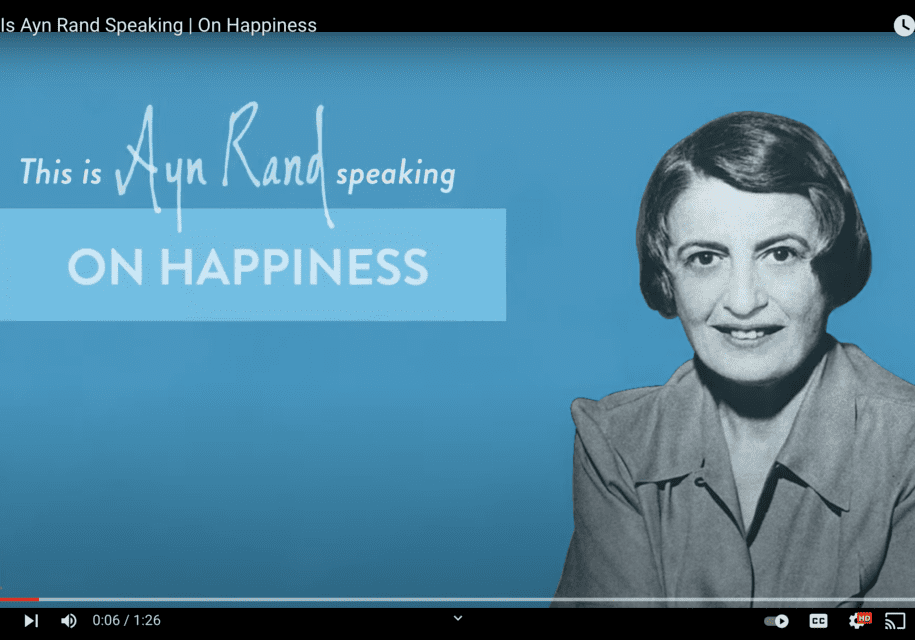 A woman is smiling and standing in front of the words " speaking on happiness ".